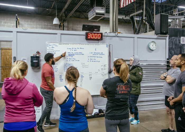 crossfit gym coach showing students workouts